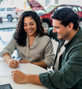 Auto Loans - Young Couple Signing Papers